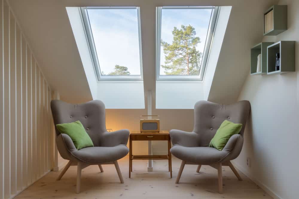 small space with a large skylight over 2 chairs.
